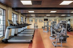 Ein Fitnessstudio mit Laufbändern, Kraftgeräten und Trainingsmatten.
