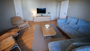 Un salon comprenant un téléviseur, un canapé, un fauteuil et une table basse.