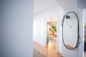 A hallway with a mirror, a door leading to a room with a chair and a plant, and a wooden floor. - Central PENTHOUSE Unirii - FREE
PARKING (București)