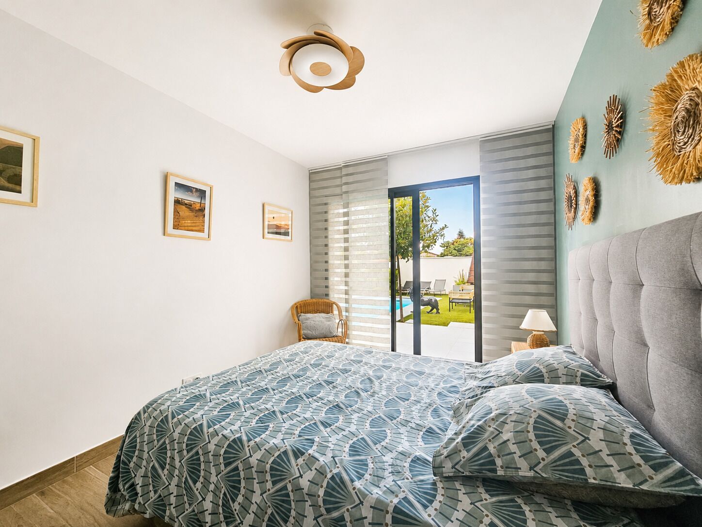 Un dormitorio con cama, una silla, una mesita de noche y vistas al exterior a través de un ventanal corredera.