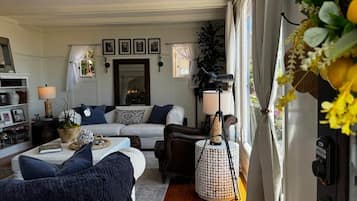 Een gezellige woonkamer met een bank, fauteuils, een salontafel en een lamp.