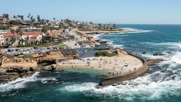 A coastal town with a beach, rocky cliffs, and a pier.