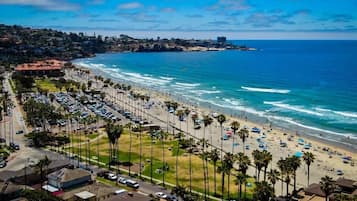 Une zone côtière avec une plage, des voitures garées et des palmiers.