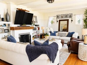A living room with a fireplace, a television, and a sofa. - Amalfi House/Hot Tub/Pizza Oven/Ocean Views (San Diego)