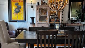 A dining area with a wooden table and chairs, a chandelier, and a framed poster on the wall.