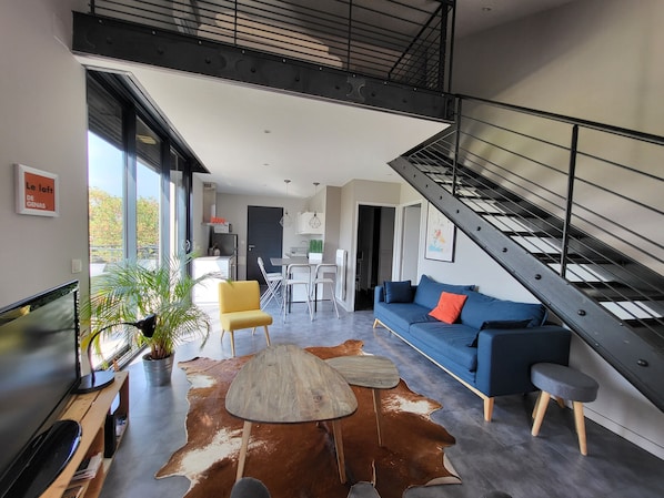 Een moderne woonkamer met een bank, een eettafel en een trap.