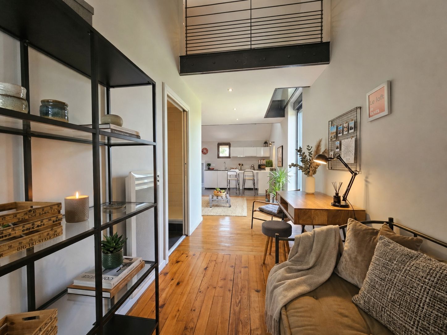 Een modern interieur met een houten vloer, een bank, een bureau en een keuken op de achtergrond.