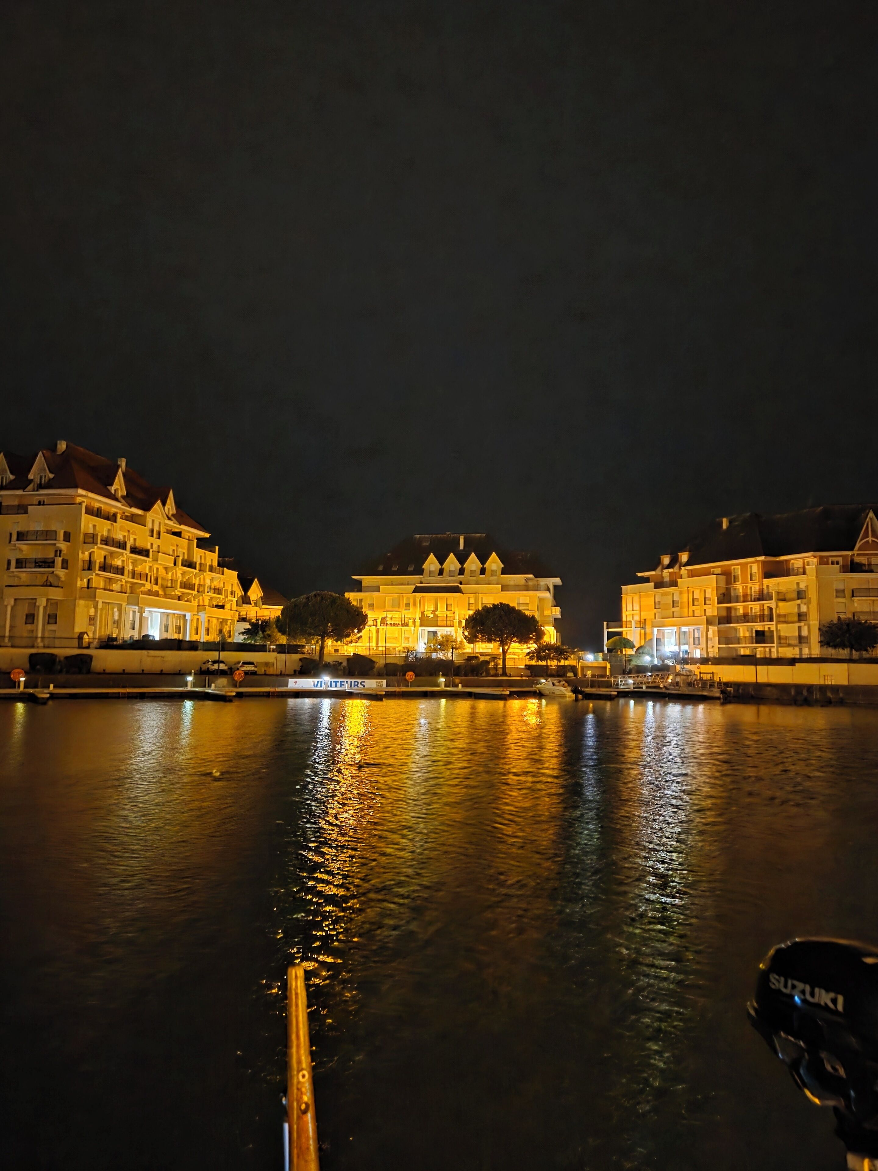 A waterfront hotel with multiple balconies and a central archway.