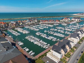 A marina with numerous boats docked, surrounded by residential buildings and a clear view of the sea.