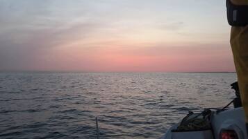 A boat's interior with a view of the sea and a sunset.