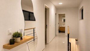 En moderne gang med en træbænk, en potteplante og et spejl.