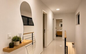 A modern hallway with a wooden bench, a potted plant, and a mirror. - Amazing home in Kolan with sauna (Kolan)