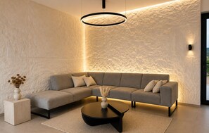 A modern living room with a sectional sofa, a round coffee table, and a textured wall. - Amazing home in Kolan with sauna (Kolan)