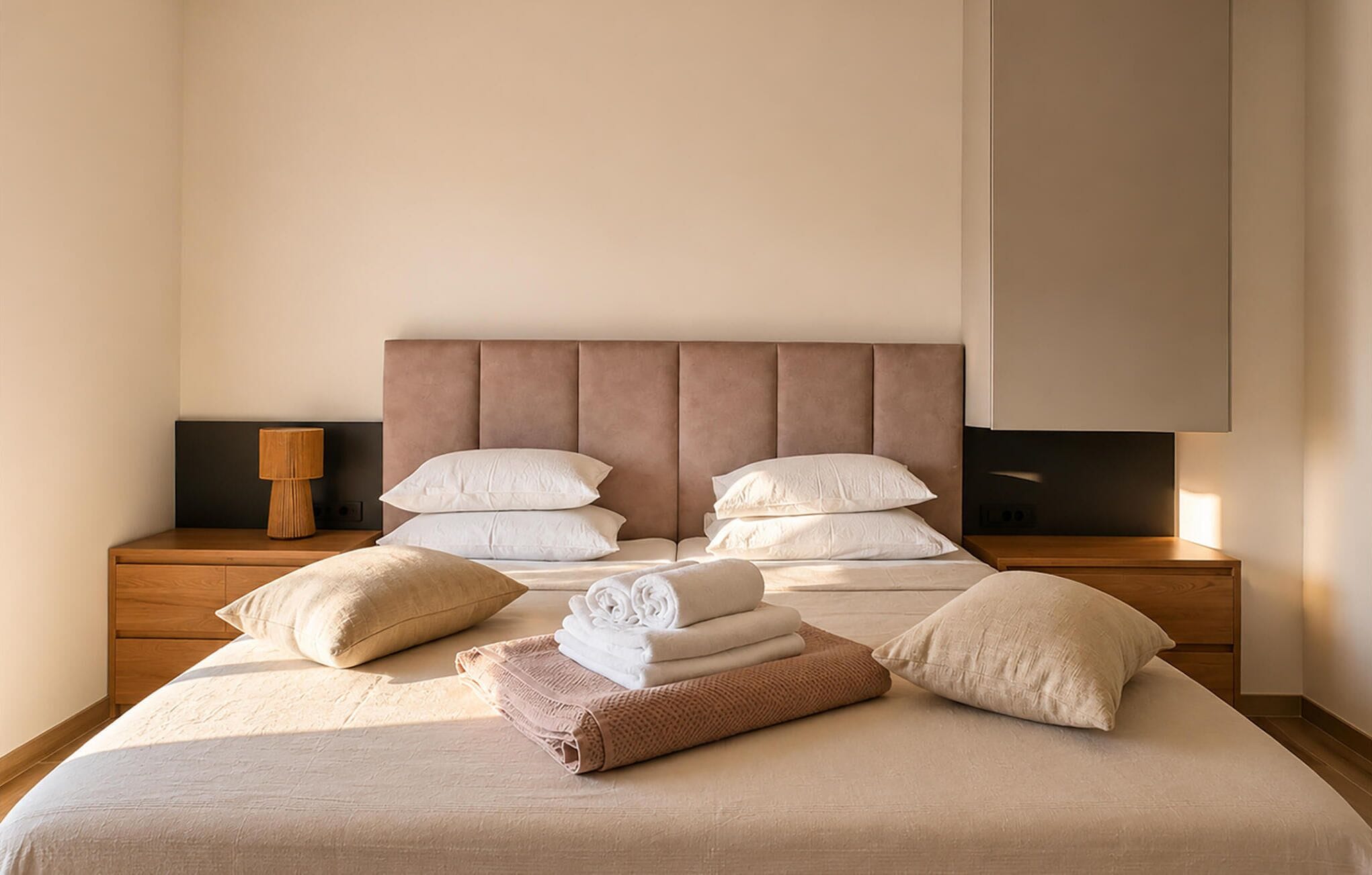 A neatly made bed with a headboard, pillows, and folded towels.
