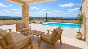 A rooftop terrace with a pool, lounge chairs, and a view of the landscape.