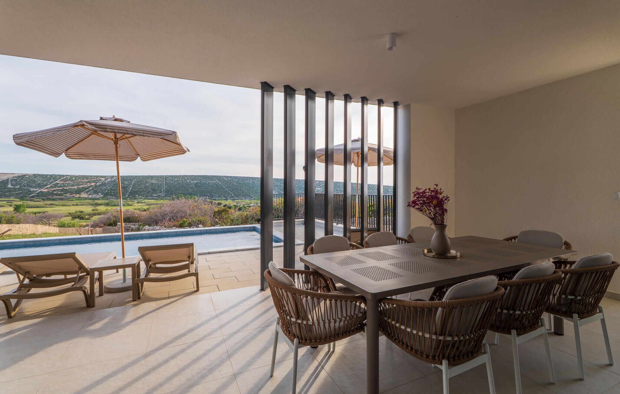 A terrace with a pool, outdoor seating, and a view of the landscape.