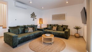 A living room with a sectional sofa, a round coffee table, a floor lamp, and a wall-mounted TV. - Amazing home in Kolan (Kolan)