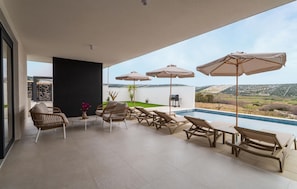 A modern outdoor patio with lounge chairs, a pool, and a view of the countryside. - Amazing home in Kolan (Kolan)