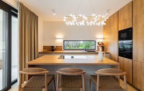 A modern kitchen with a central island, bar stools, a built-in oven, and a large window with a view. - Amazing home in Kolan (Kolan)