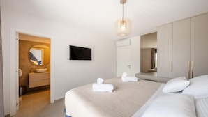 A bedroom with a bed, a TV, a mirror, and a bathroom with a sink and towel rack. - Amazing home in Kolan (Kolan)