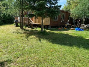 A wooden cabin with a deck, surrounded by grass and trees. - Waterfront Chalet! The Getaway You Need! (Lantier)