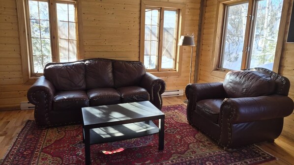 A room with a leather sofa, a matching armchair, and a coffee table. - Waterfront Chalet! The Getaway You Need! (Lantier)