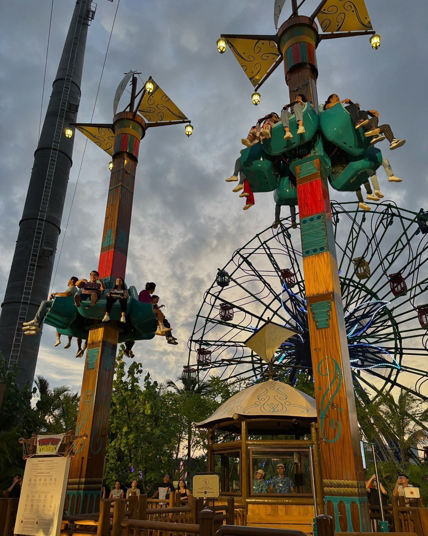 A Ferris wheel with cabins and a tall structure with a pointed top.