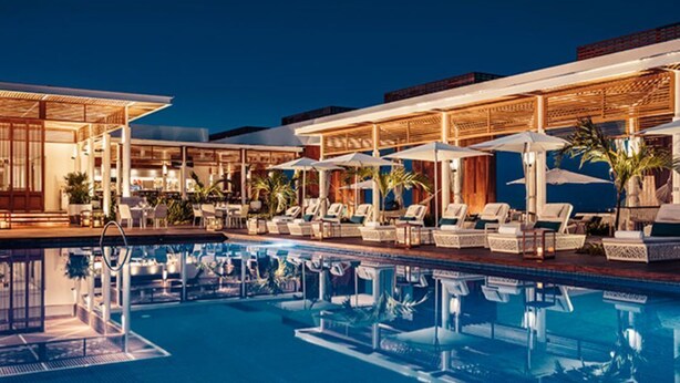 A poolside area with lounge chairs and umbrellas, a clear pool, and a building with a covered walkway. - The Grand Bliss Nuevo Vallarta Resort 2 bedrooms and AC at Vidanta Resort (Nayarit.)