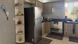 Una cocina moderna con refrigerador empotrado, armarios de madera y una pequeña isla con estantes.