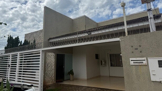 Un edificio moderno con techo plano, entrada cubierta y una puerta de seguridad.