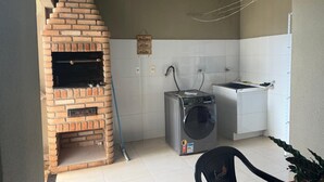 A compact kitchen with a brick oven, a washing machine, and a sink. - Cozy, high-standard house near Diacuí Lake. (Jataí)