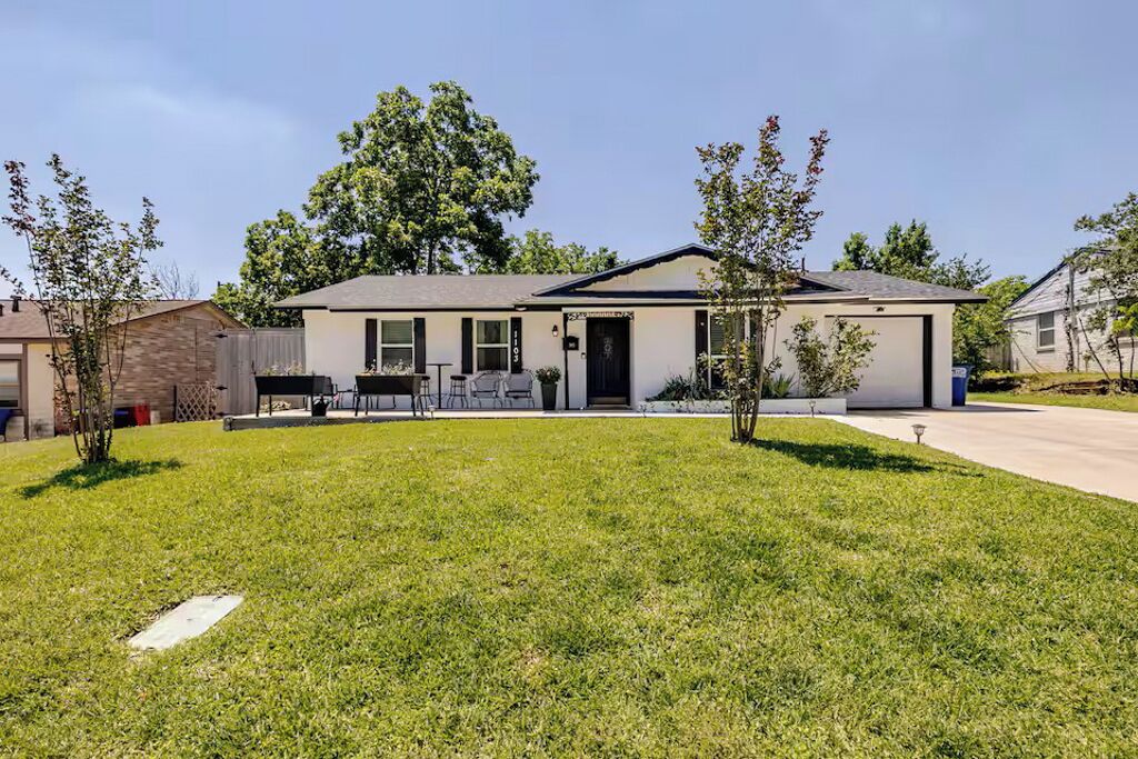 A single-story residential house with a front yard, a garage, and a small patio area.
