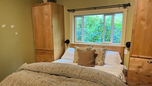 Un dormitorio con cama, armario de madera y ventana con vistas a zonas verdes.