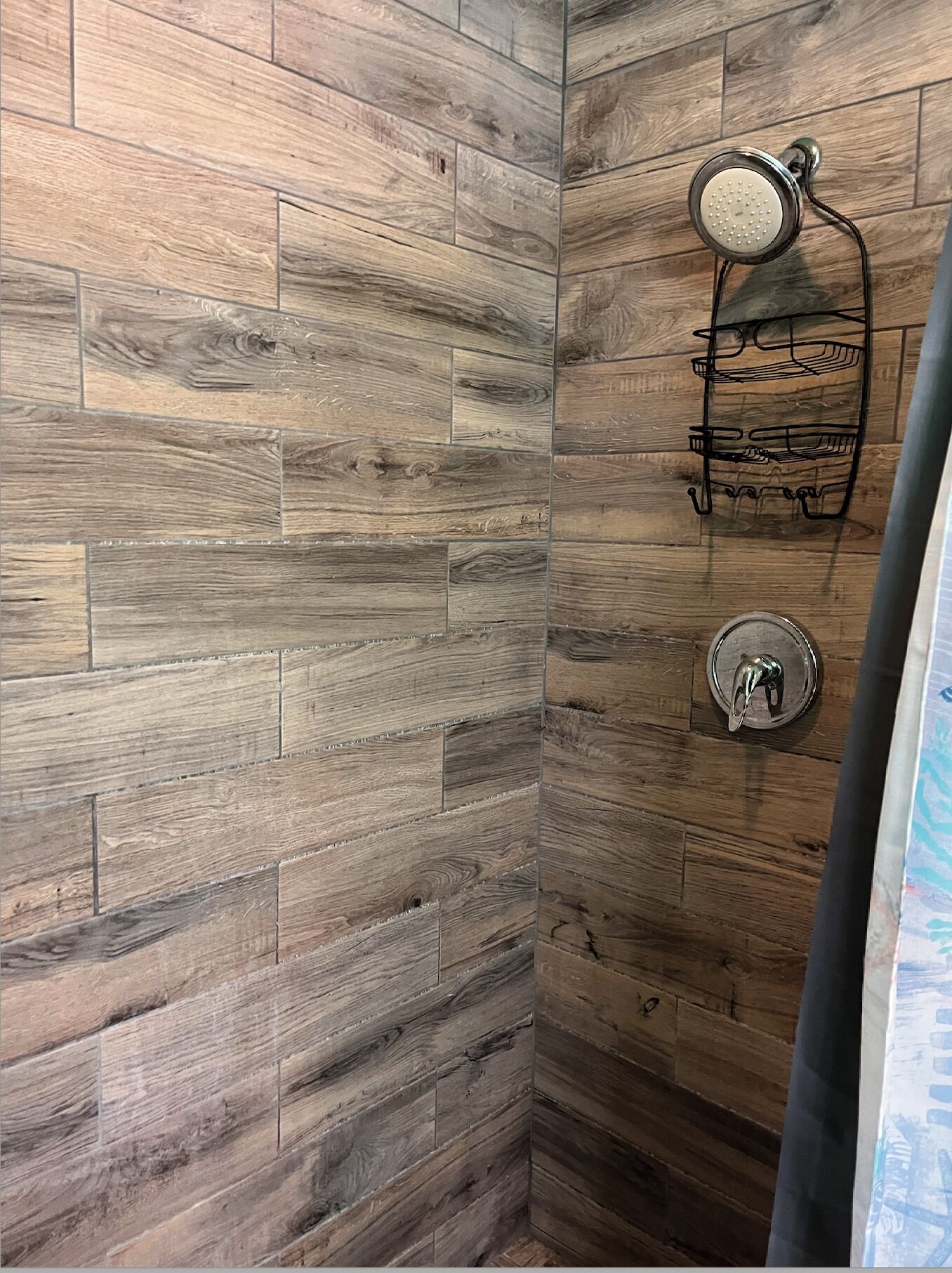 Un espace douche agrémenté d’un mur en bois et d’un pommeau de douche fixé au mur.