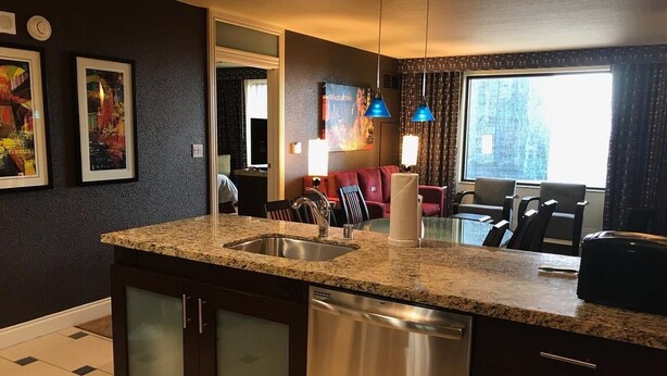 A kitchen with granite countertops, a dishwasher, and a dining area with a red couch and chairs.