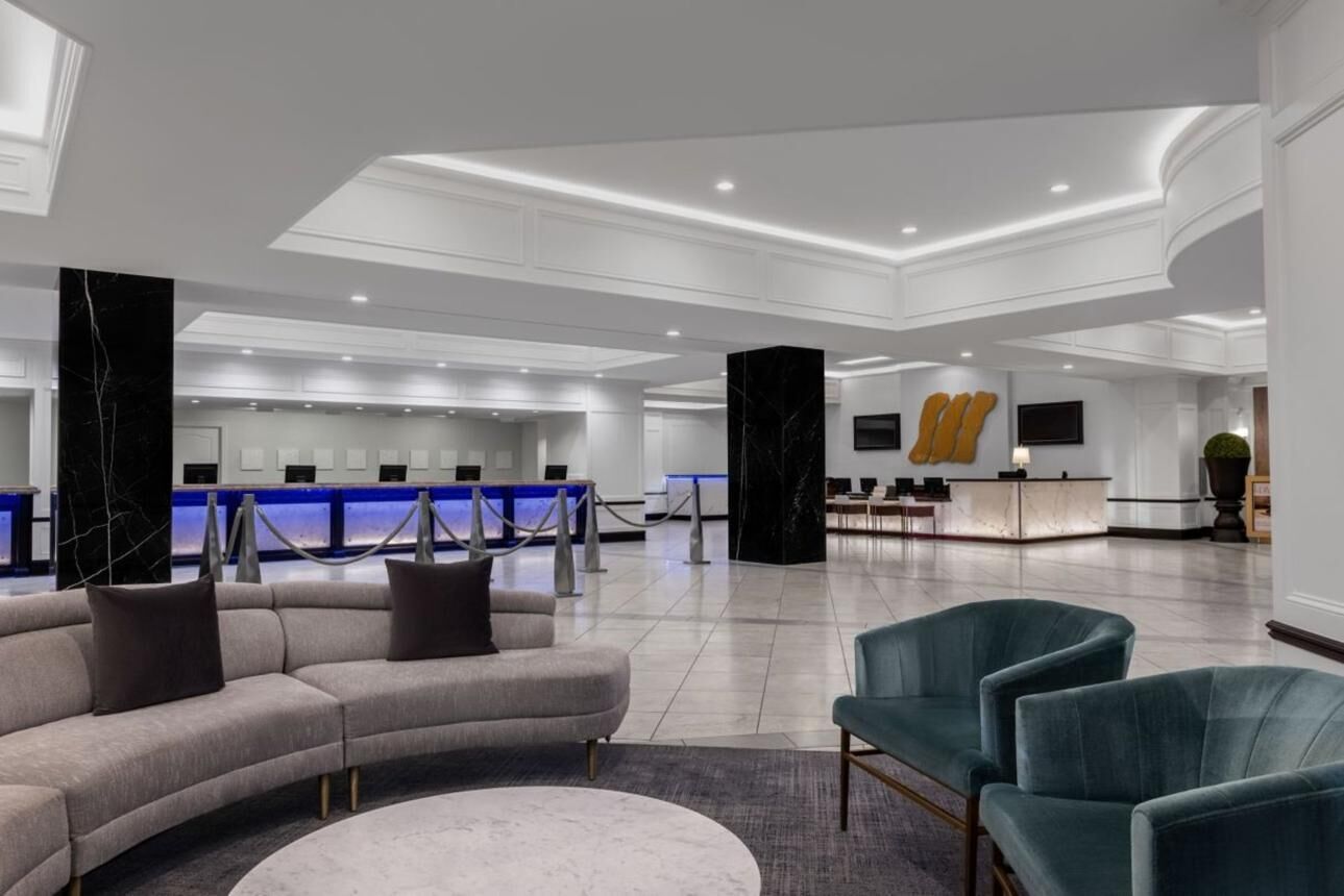 Un hall d’entrée moderne avec un comptoir d’accueil, un canapé incurvé et des fauteuils turquoise.