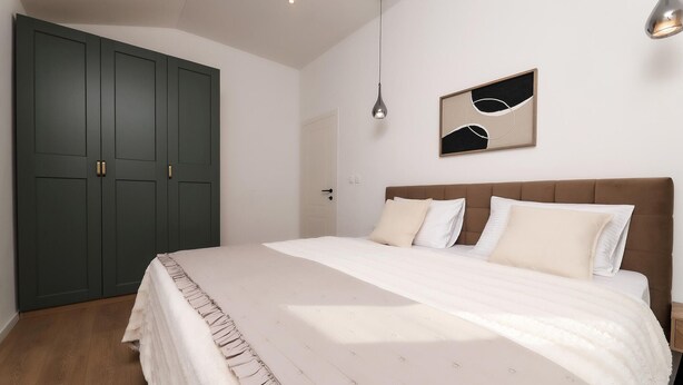 A bedroom with a large bed, a wardrobe, a hanging light, and a wall art piece. - Pet friendly home in Krk (Krk)