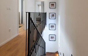 Eine Treppe mit schwarzen Geländern, einem Holzboden und gerahmten Bildern an der Wand.
