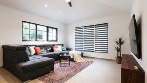 A modern living room with a sectional sofa, a ceiling fan, large windows with blinds, and a flat-screen TV mounted on the wall. - Pet friendly home in Krk (Krk)