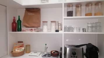 A kitchen with white cabinets, a toaster, a bag of flour, and various kitchen items on the shelves.