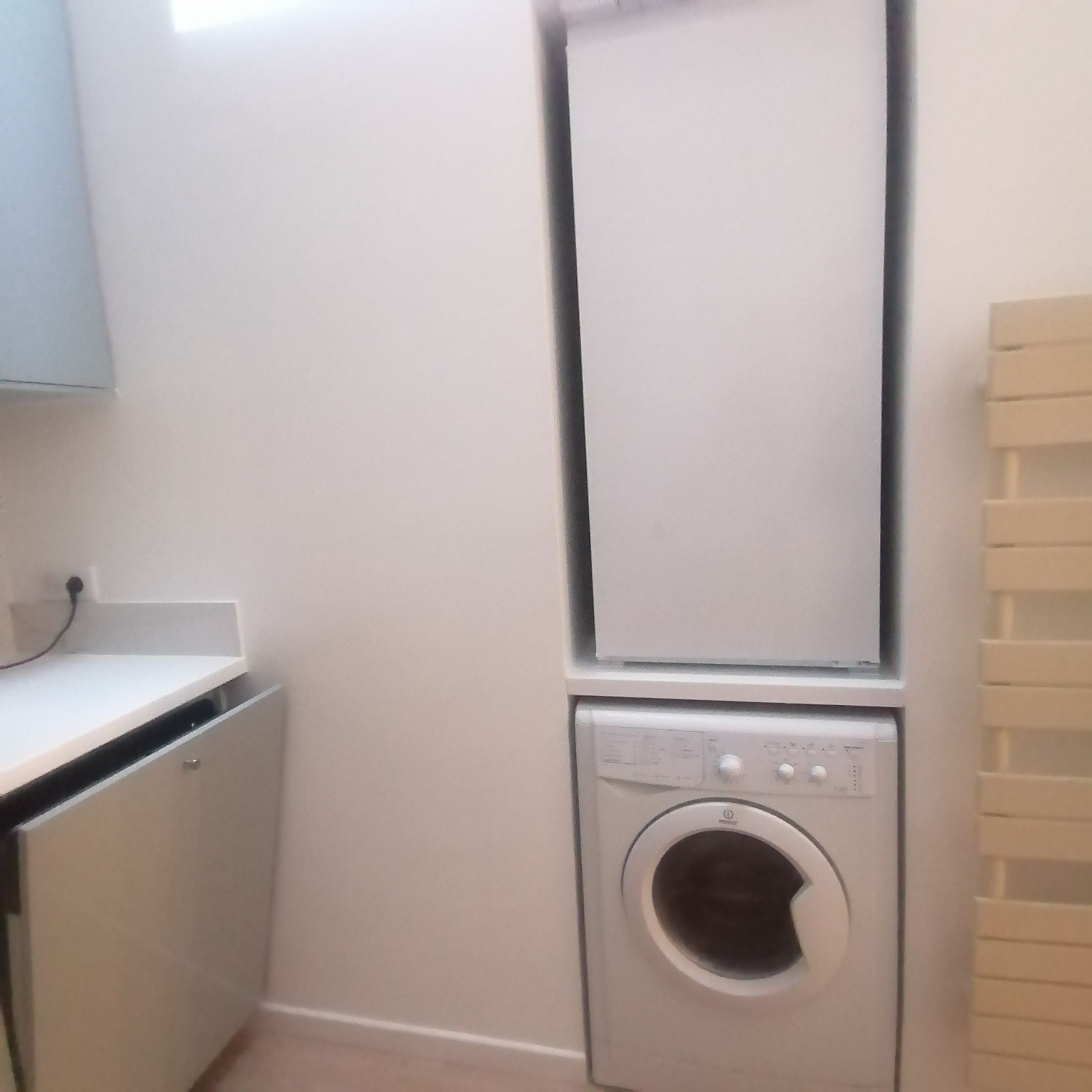 A laundry room with a washing machine and dryer stacked on top of each other.