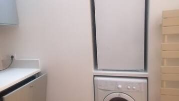 A laundry room with a washing machine and dryer stacked on top of each other.