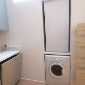 A laundry room with a washing machine and dryer stacked on top of each other. - Atypical, rare house in the historic and quiet heart of Paris (Paris)