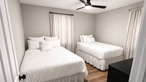 Quarto com duas camas, um ventilador de teto e piso de madeira.