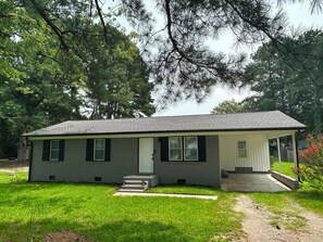 A single-story house with a front porch, a small front yard, and a garage. - Newly Renovated 3BR Home - Near Raleigh - Sleeps 7 (Zebulon)