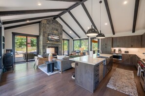 Une cuisine spacieuse dotée d’un grand îlot central, d’une cheminée en pierre et offrant une vue sur l’extérieur.