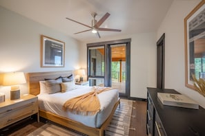 A bedroom with a bed, bedside tables, a ceiling fan, a window, and a door leading to an outdoor area.