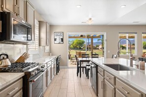 A modern kitchen with a large island, stainless steel appliances, and a view to the outdoors.