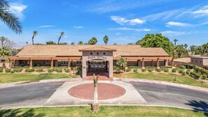 A hotel with a covered entrance, palm trees, and a clear sky. - The Royal Fairway | 5BR/4BA Pool, Spa & Golf Views (Indio)
