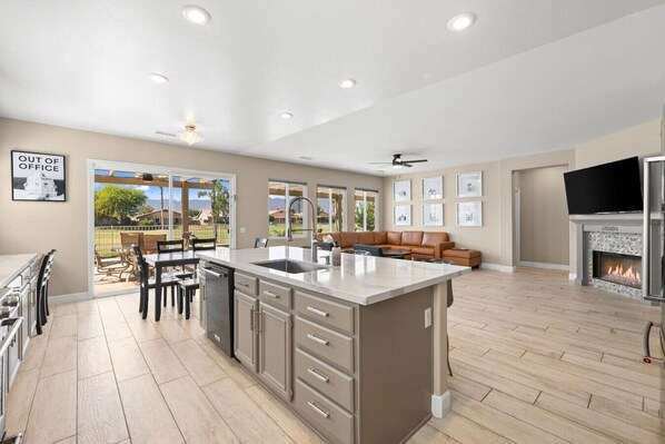 A spacious kitchen with a large island, a dining area, and a living room with a fireplace.